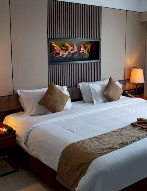 A well-decorated hotel room with a large bed, soft lighting, bedside lamps, and a cozy ambiance is shown.