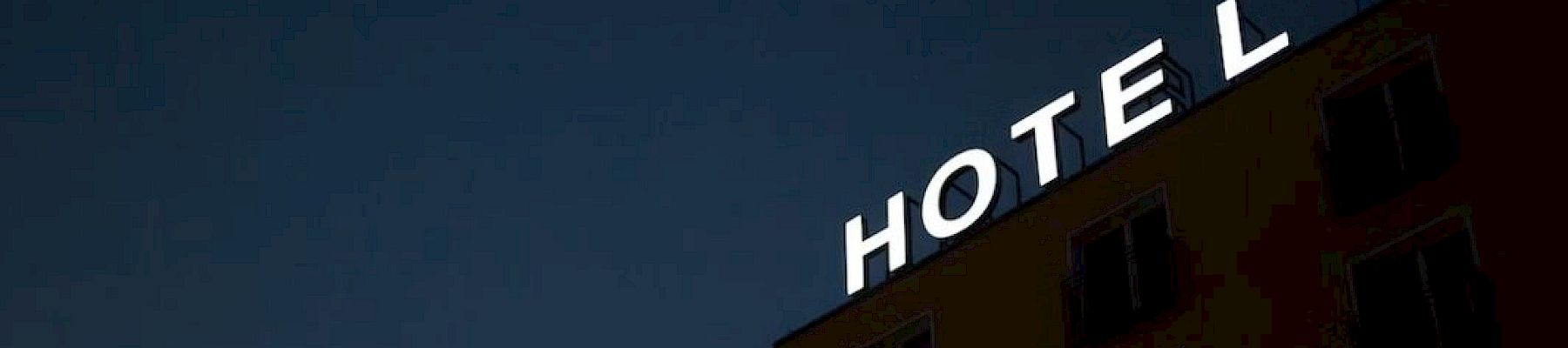 A building with a "HOTEL" sign is shown against a dark sky, with some rooms visible.