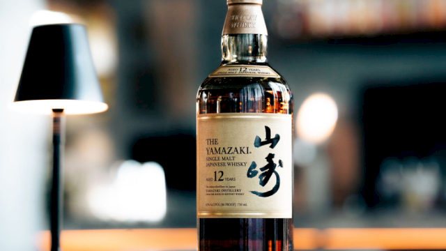 A bottle of The Yamazaki 12-year-old whiskey on a bar counter, with a blurred background and warm lighting.