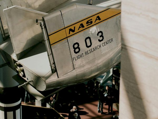 The image shows part of a NASA aircraft with the number 803 and "Flight Research Center" visible in an indoor setting.