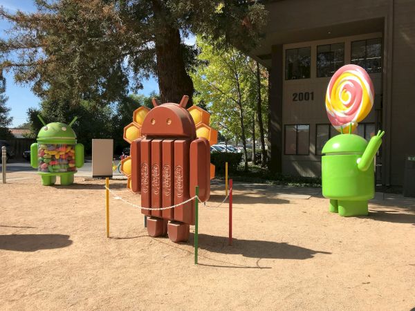 Statues of Android mascots themed after different versions: Android KitKat, Android Lollipop, and Android Jelly Bean are shown outside a building.