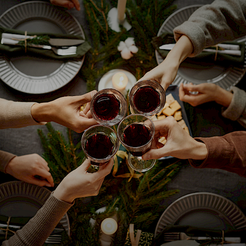 Friends cheers around a table set for a cozy dinner, clinking glasses in a circular toast.