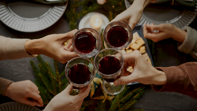 Friends cheers around a table set for a cozy dinner, clinking glasses in a circular toast.