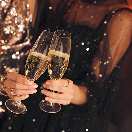 Two people clinking champagne flutes, festive night vibes and sparkling lights.