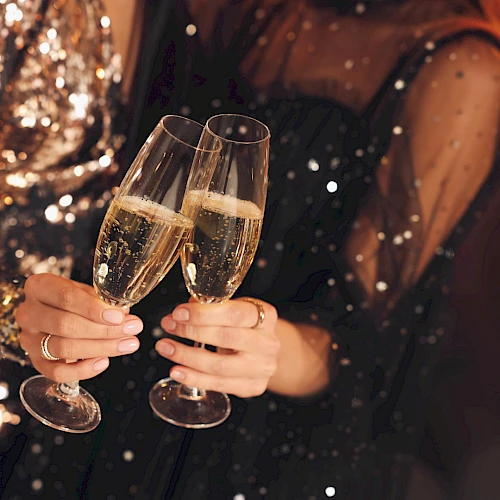 Two people clinking champagne flutes, festive night vibes and sparkling lights.