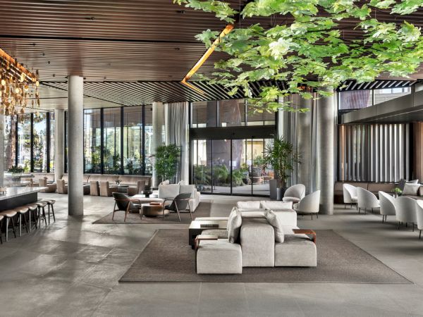 A modern hotel lobby with open space, contemporary seating, plants, large windows, and a calm, inviting atmosphere.