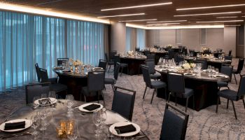 This image shows an elegantly set banquet hall with round tables, blue chairs, and dim lighting, creating a formal dining atmosphere.