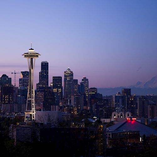 Seattle skyline at dusk, featuring the Space Needle with Mount Rainier in the background.